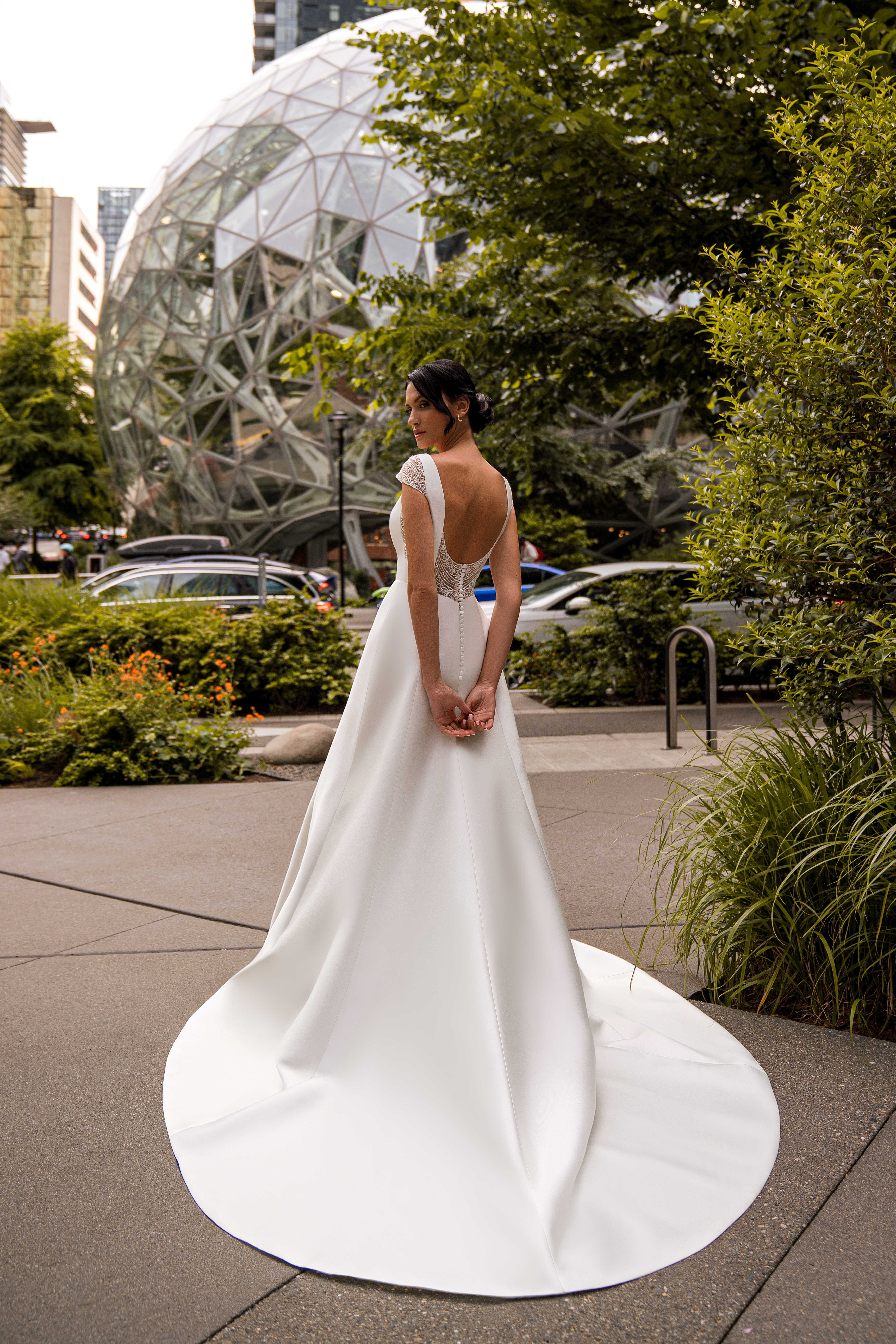An unsurpassed minimalist wedding dress with winged straps and a train skirt is a true masterpiece of elegance.-1